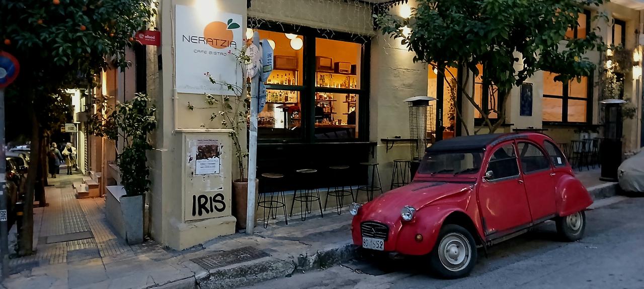 Ein Café mit Licht in den Fenstern, ein roter 2CV parkt davor