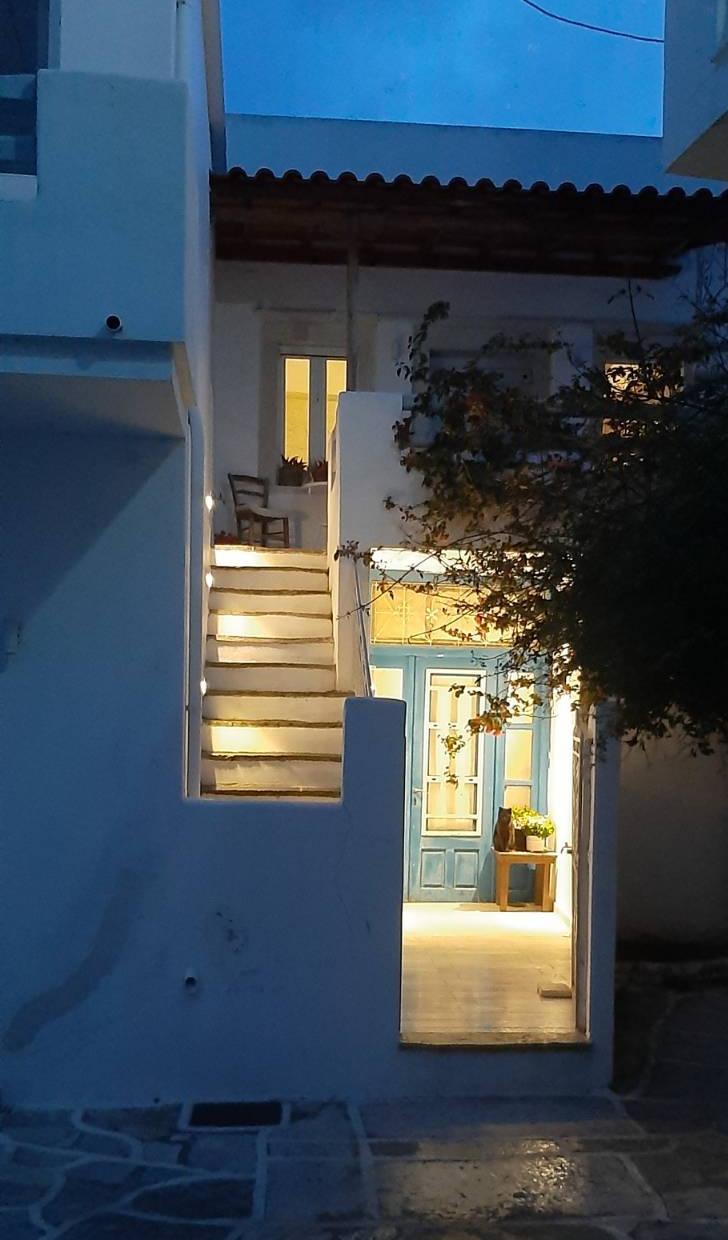 Der Eingang und die Aussentreppe eines Hauses in einem Dorf, die Fenster sind erleuchtet und die Treppe ist beleuchtet